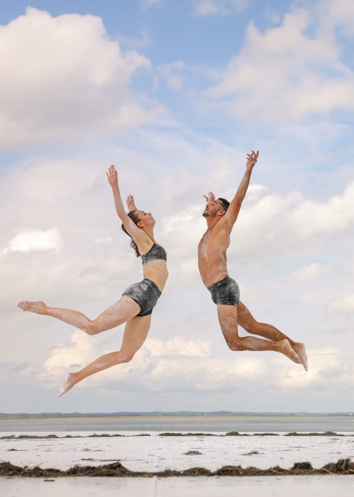 2 danseurs face à face en plein saut sur fond de ciel nuageux
