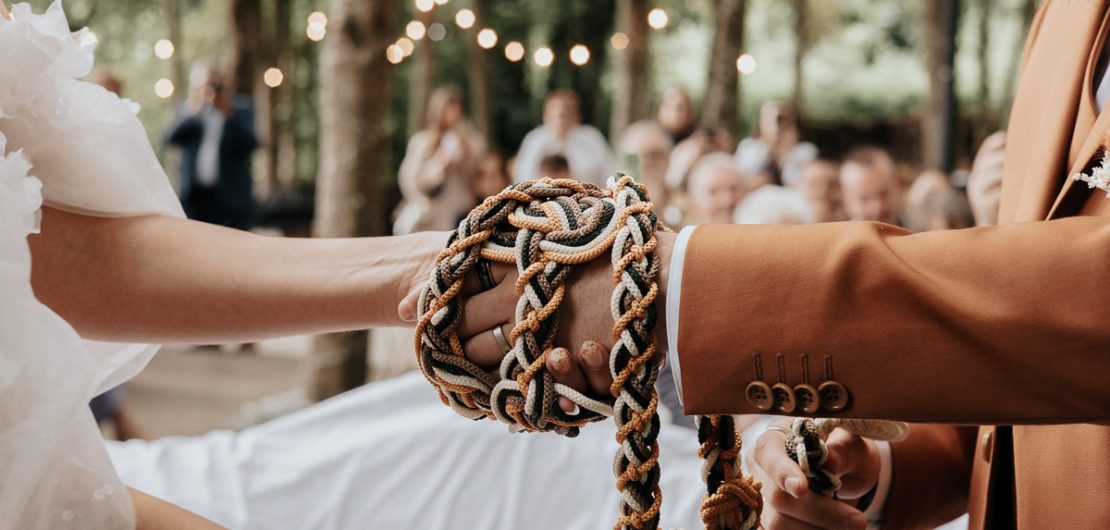 Photographe de mariage à Bordeaux — cérémonie laïque avec rituel des mains liées dans un cadre boisé.