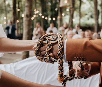 Photographe de mariage à Bordeaux — cérémonie laïque avec rituel des mains liées dans un cadre boisé.