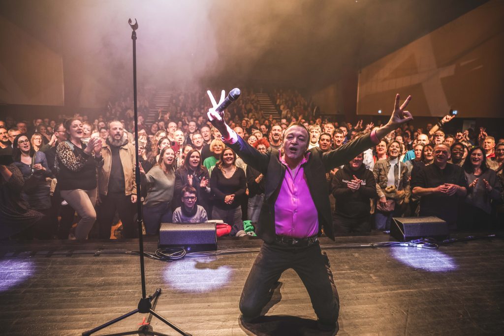 Cali sur scène devant une salle comble